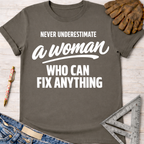 Women's funny woodworking graphic tee shirt for female woodworkers, makers, and DIY builders — Sawdust & Ponytails. Dark gray cotton tee with "Never Underestimate a Woman Who Can Fix Anything" in white text.