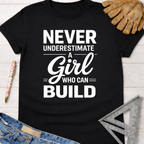 Black cotton Women's funny woodworking graphic tee shirt for female woodworkers, makers, and DIY builders — Sawdust & Ponytails, with white text "Never Underestimate A Girl Who Can Build".