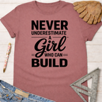 Women's funny woodworking graphic tee shirt for female woodworkers, makers, and DIY builders — Sawdust & Ponytails. Mauve cotton t-shirt with "Never Underestimate A Girl Who Can Build" in black text.