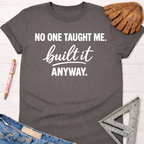 Charcoal gray women's funny woodworking graphic tee shirt with "NO ONE TAUGHT ME. built it ANYWAY." in white text, for female woodworkers, makers, and DIY builders — Sawdust & Ponytails
