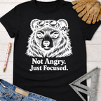 Black cotton tee with "Not Angry. Just Focused." text and a bear wearing goggles. Women's funny woodworking graphic tee shirt for female woodworkers, makers, and DIY builders — Sawdust & Ponytails