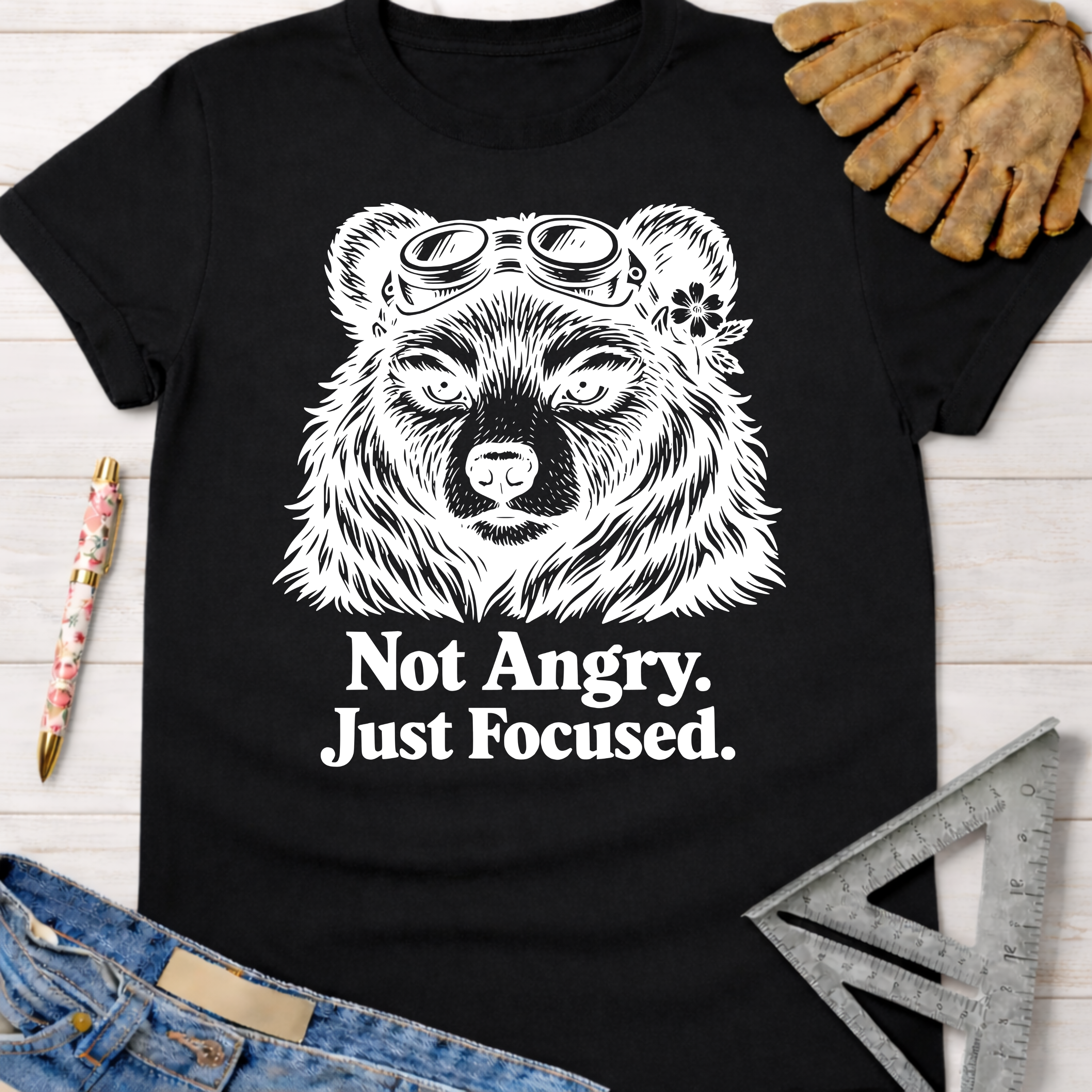 Black cotton tee with "Not Angry. Just Focused." text and a bear wearing goggles. Women's funny woodworking graphic tee shirt for female woodworkers, makers, and DIY builders — Sawdust & Ponytails