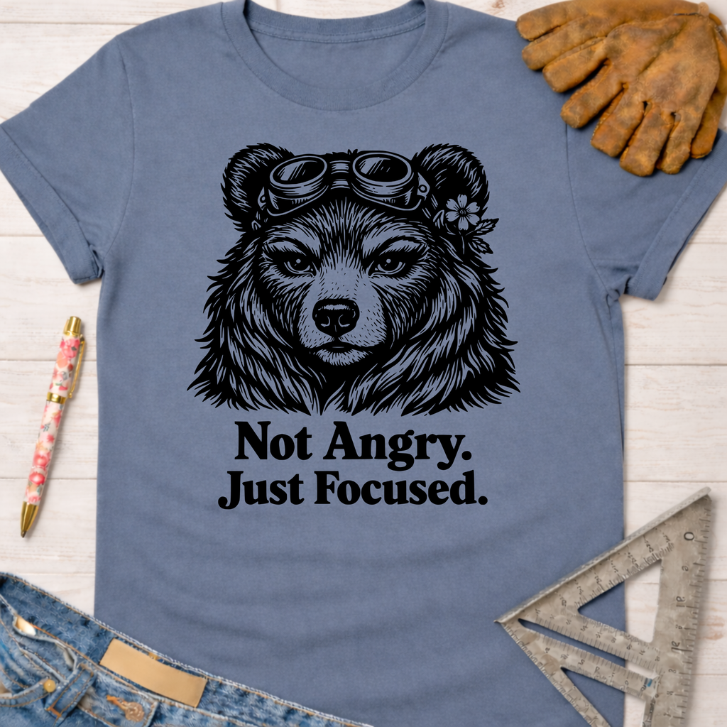 Women's funny woodworking graphic tee shirt for female woodworkers, makers, and DIY builders — Sawdust & Ponytails. Blue cotton tee with "Not Angry. Just Focused." text and a bear wearing goggles.