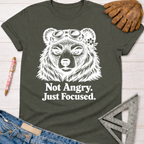 Women's funny woodworking graphic tee shirt for female woodworkers, makers, and DIY builders — Sawdust & Ponytails. Dark gray cotton tee with white "Not Angry. Just Focused." text and a bear wearing goggles and a flower.