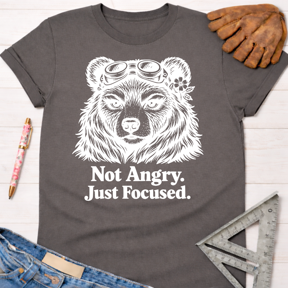 Charcoal gray women's tee with a white "Not Angry. Just Focused." bear wearing goggles. Women's funny woodworking graphic tee shirt for female woodworkers, makers, and DIY builders — Sawdust & Ponytails
