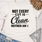 Women's funny woodworking graphic tee shirt for female woodworkers, makers, and DIY builders — Sawdust & Ponytails. Cream t-shirt with "Not Every Cut Is Clean Neither Am I" in black text.