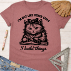 Women's funny woodworking graphic tee shirt for female woodworkers, makers, and DIY builders — Sawdust & Ponytails. Mauve t-shirt with a black graphic of a cat using a hand plane, text "I'm not like other girls, I build things".
