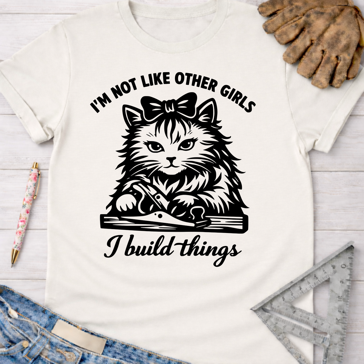 Women's funny woodworking graphic tee shirt for female woodworkers, makers, and DIY builders — Sawdust & Ponytails. White cotton tee with a black graphic of a cat using a hand plane, text "I'm not like other girls, I build things.