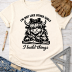 Women's funny woodworking graphic tee shirt for female woodworkers, makers, and DIY builders — Sawdust & Ponytails. Cream cotton tee with a black graphic of a Highland cow using a hand plane, text "I'm not like other girls I build things".