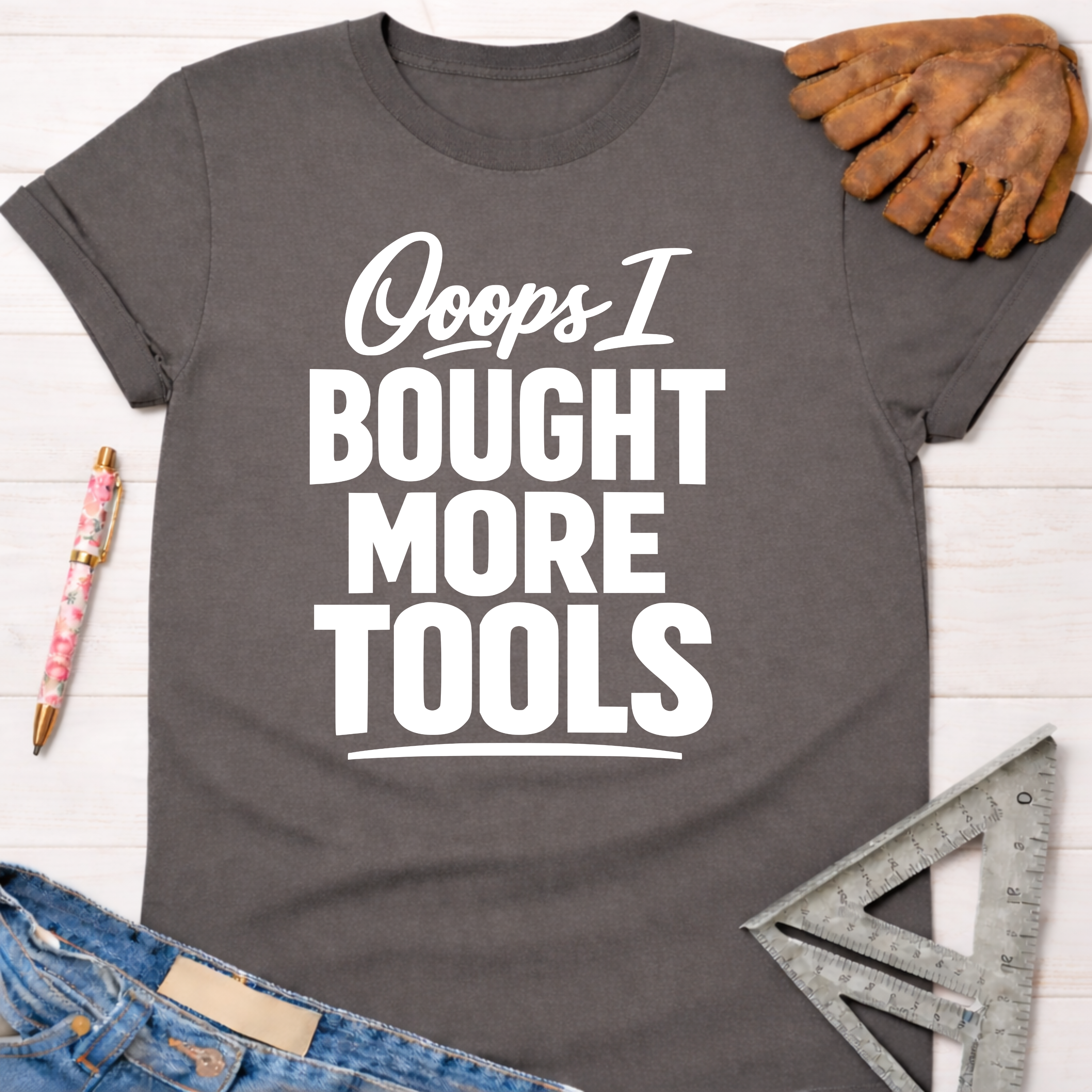 Women's funny woodworking graphic tee shirt for female woodworkers, makers, and DIY builders — Sawdust & Ponytails. Dark gray cotton tee with "Ooops I Bought More Tools" in white text.
