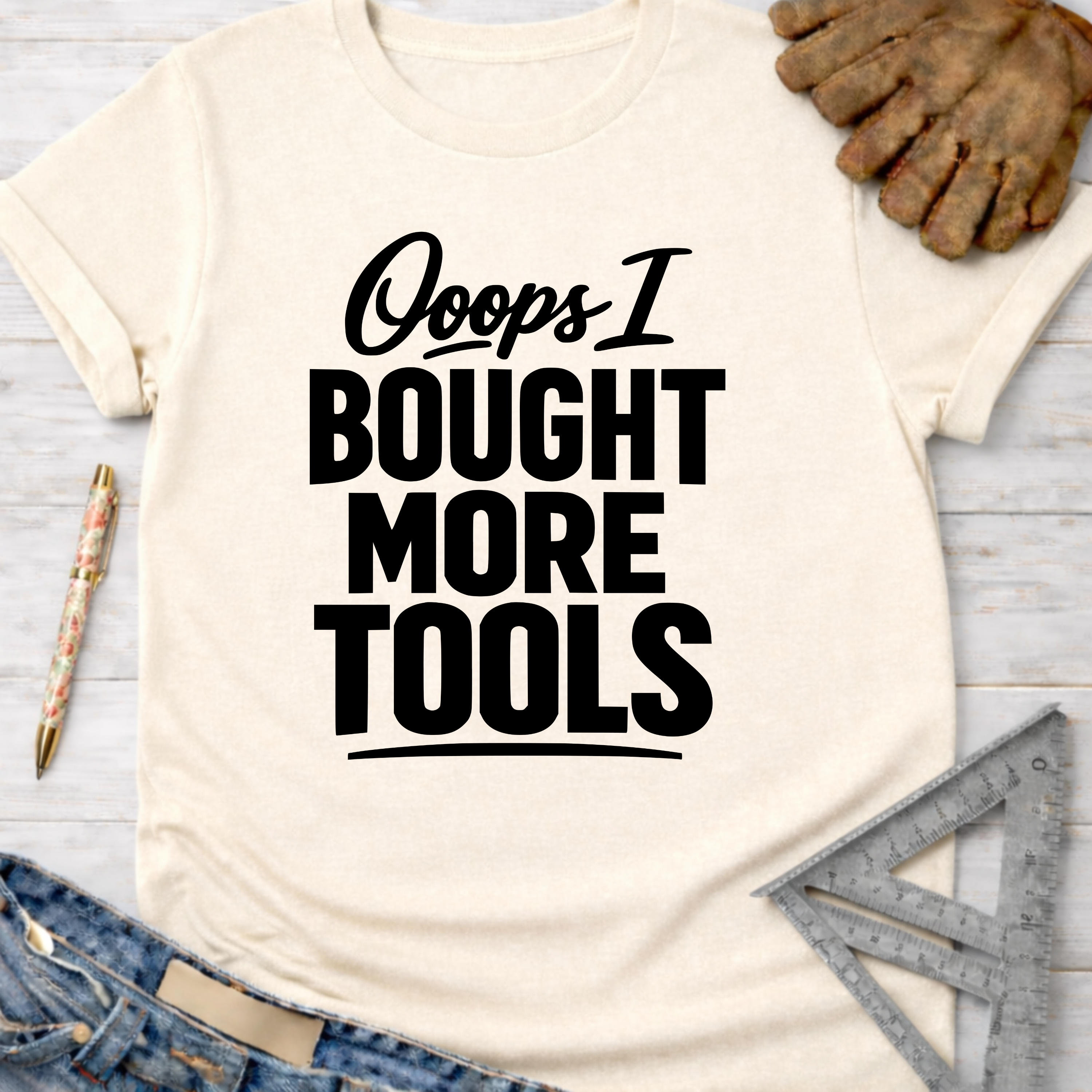 Women's funny woodworking graphic tee shirt for female woodworkers, makers, and DIY builders — Sawdust & Ponytails. Cream short-sleeve t-shirt with "Ooops I BOUGHT MORE TOOLS" in black text.