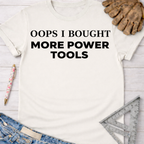 Women's funny woodworking graphic tee shirt for female woodworkers, makers, and DIY builders — Sawdust & Ponytails. White cotton t-shirt with "OOPS I BOUGHT MORE POWER TOOLS" in black text.