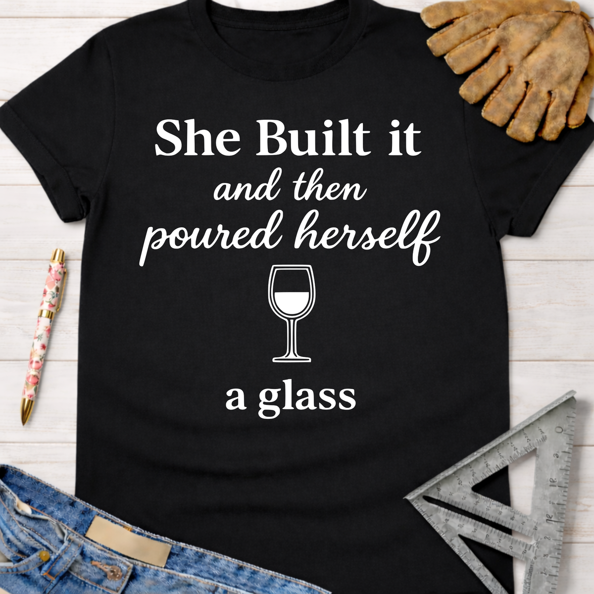 Black cotton tee with "She Built it and then poured herself a glass" graphic, wine glass icon. Women's funny woodworking graphic tee shirt for female woodworkers, makers, and DIY builders — Sawdust & Ponytails.