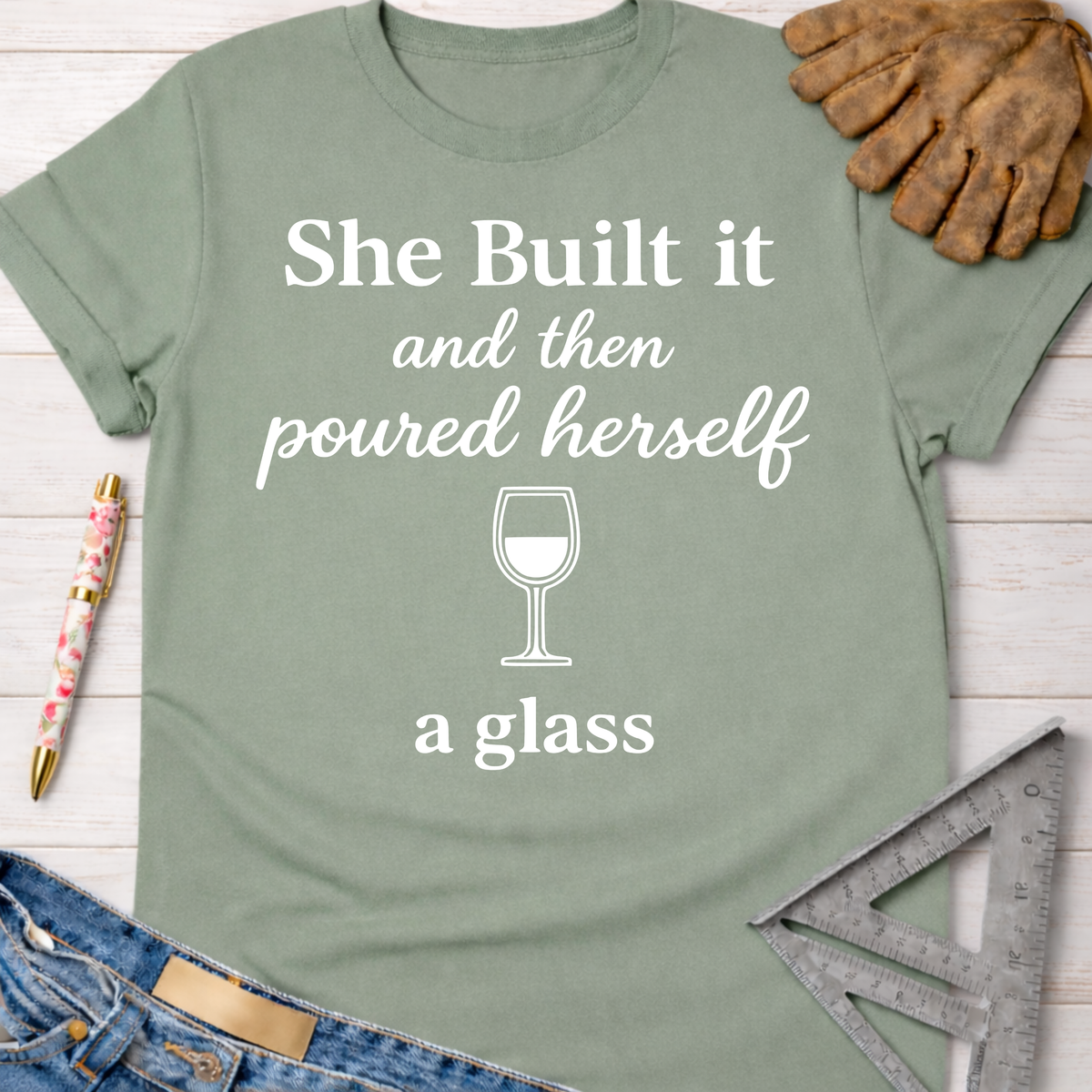 Women's funny woodworking graphic tee shirt for female woodworkers, makers, and DIY builders — Sawdust & Ponytails. Sage green cotton tee with "She Built it and then poured herself a glass" graphic.