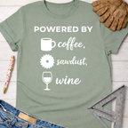 Women's funny woodworking graphic tee shirt for female woodworkers, makers, and DIY builders — Sawdust & Ponytails. Sage green cotton tee with "Powered By coffee, sawdust, wine" graphic.
