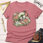 Pink women's t-shirt with a colorful floral miter saw graphic, styled on a white wooden surface.