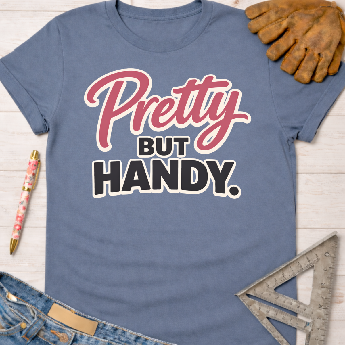 Women's funny woodworking graphic tee shirt for female woodworkers, makers, and DIY builders — Sawdust & Ponytails. Blue cotton t-shirt with "Pretty BUT HANDY." graphic.