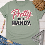 Sage green cotton "Pretty But Handy" graphic tee, women's funny woodworking shirt for makers and DIY builders — Sawdust & Ponytails.
