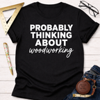 Black cotton tee with "PROBABLY THINKING ABOUT woodworking" in white text. Women's funny woodworking graphic tee shirt for female woodworkers, makers, and DIY builders — Sawdust & Ponytails.