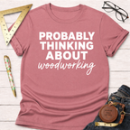 Women's funny woodworking graphic tee shirt for female woodworkers, makers, and DIY builders — Sawdust & Ponytails. Mauve pink short-sleeve tee with "PROBABLY THINKING ABOUT woodworking" in white text.