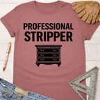 Women's funny woodworking graphic tee shirt for female woodworkers, makers, and DIY builders — Sawdust & Ponytails. Mauve t-shirt with "PROFESSIONAL STRIPPER" text and a dresser graphic.