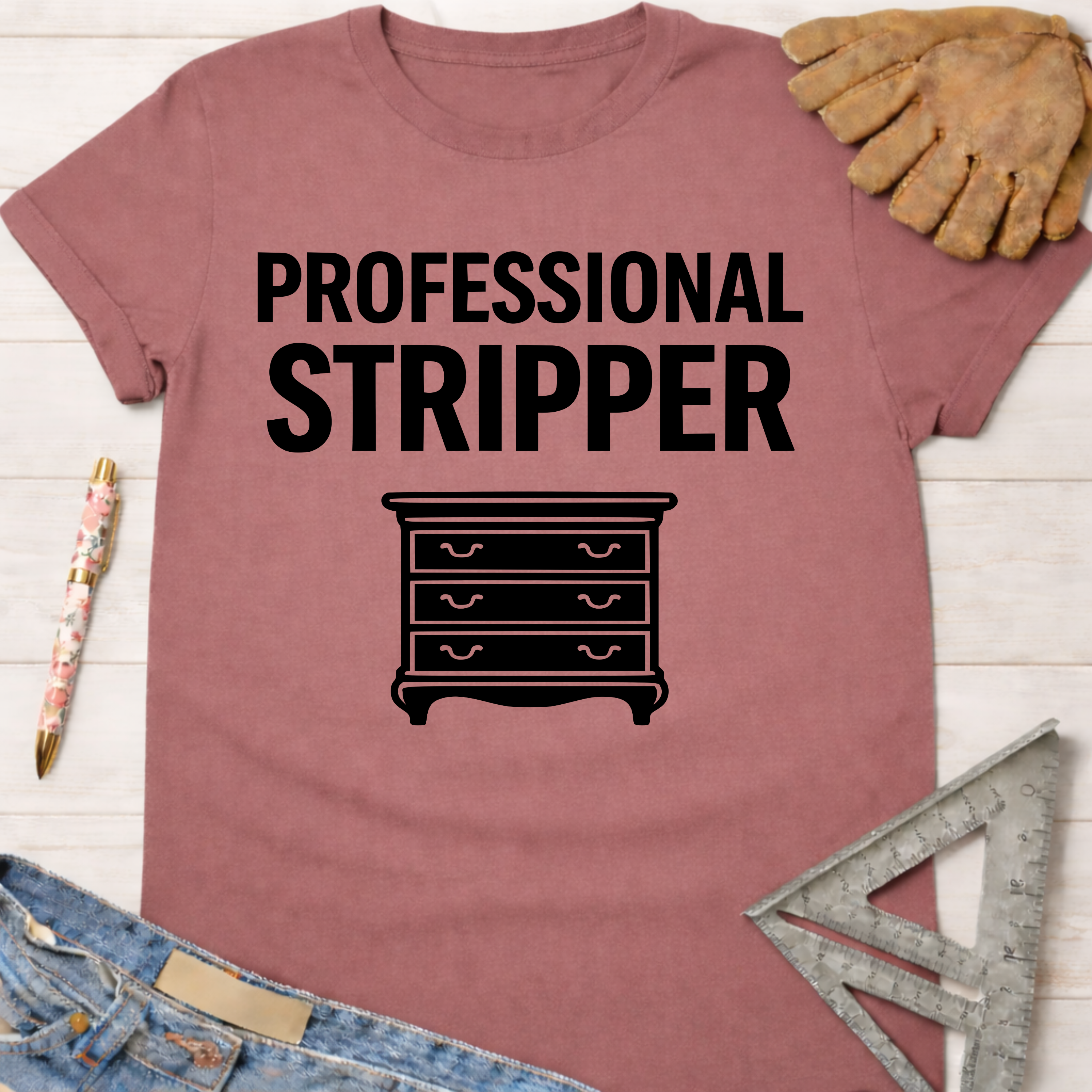 Women's funny woodworking graphic tee shirt for female woodworkers, makers, and DIY builders — Sawdust & Ponytails. Mauve t-shirt with "PROFESSIONAL STRIPPER" text and a dresser graphic.