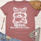 Women's funny woodworking graphic tee shirt for female woodworkers, makers, and DIY builders — Sawdust & Ponytails. Mauve t-shirt with a white graphic of a raccoon wearing sunglasses and holding a hammer, with text "Relax. She's always got a plan.