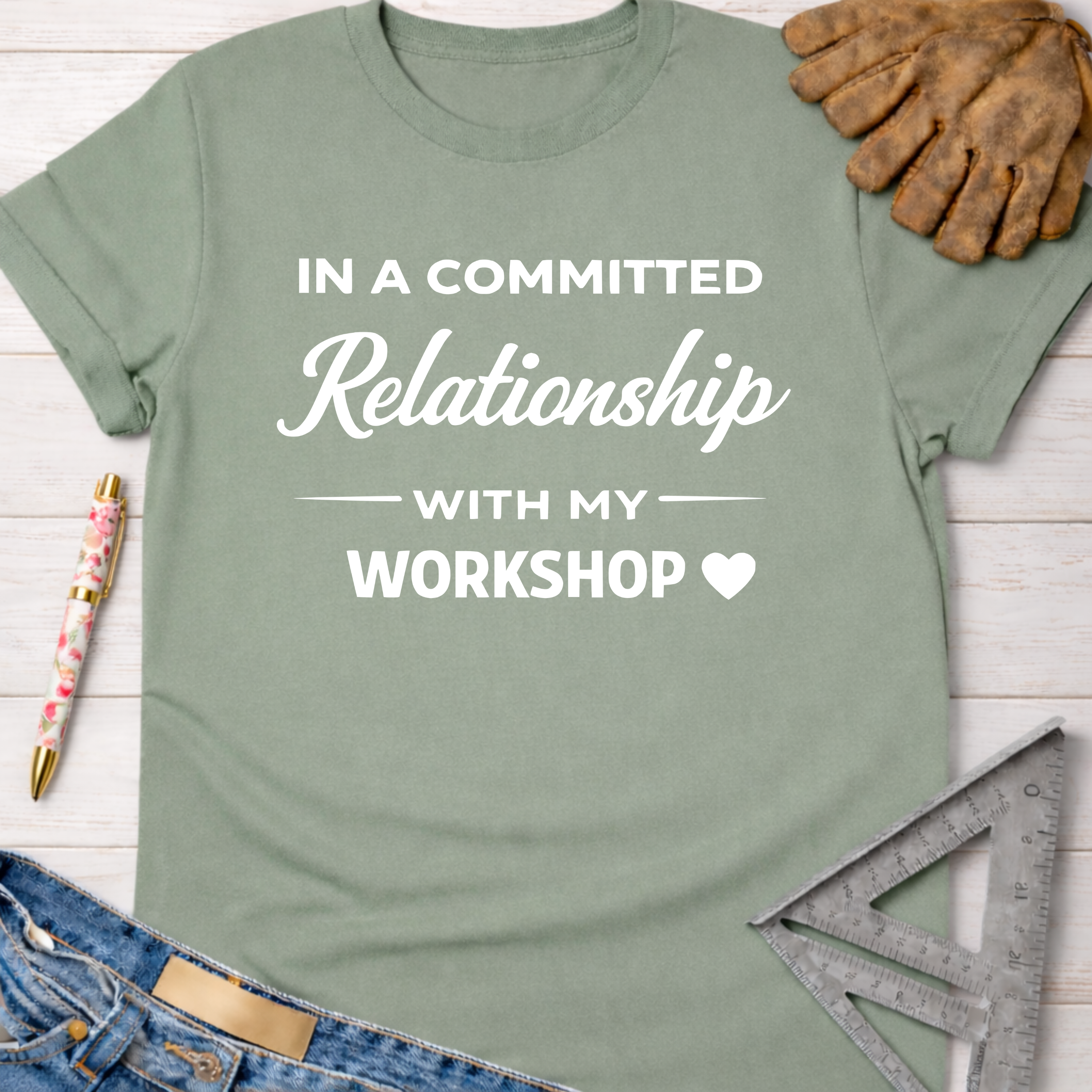 Women's funny woodworking graphic tee shirt for female woodworkers, makers, and DIY builders — Sawdust & Ponytails. Sage green cotton tee with "In a Committed Relationship With My Workshop" text.