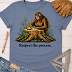 Women's funny woodworking graphic tee shirt for female woodworkers, makers, and DIY builders — Sawdust & Ponytails. Blue cotton tee with Bigfoot sanding wood on a tree stump, "Respect the process." text.