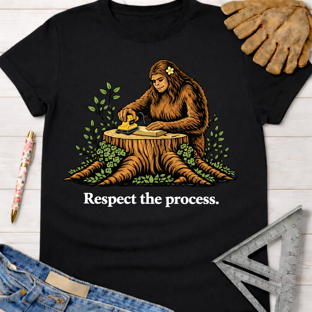 Black women's funny woodworking graphic tee shirt for female woodworkers, makers, and DIY builders — Sawdust & Ponytails. Features Bigfoot sanding wood on a tree stump with "Respect the process." text.