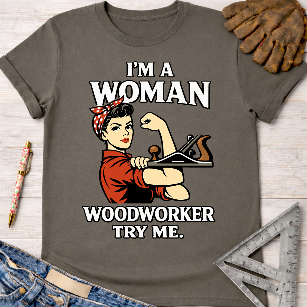 Women's funny woodworking graphic tee shirt for female woodworkers, makers, and DIY builders — Sawdust & Ponytails. Gray cotton tee with "I'm A Woman Woodworker Try Me" graphic featuring Rosie the Riveter holding a wood plane.