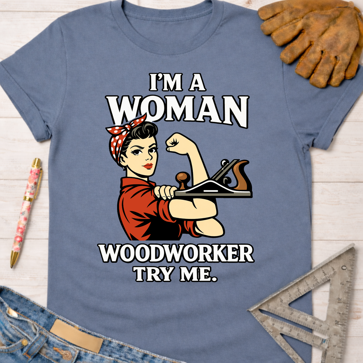 Women's funny woodworking graphic tee shirt for female woodworkers, makers, and DIY builders — Sawdust & Ponytails. Light blue cotton tee with "I'm A Woman Woodworker Try Me" graphic featuring Rosie the Riveter holding a hand plane.