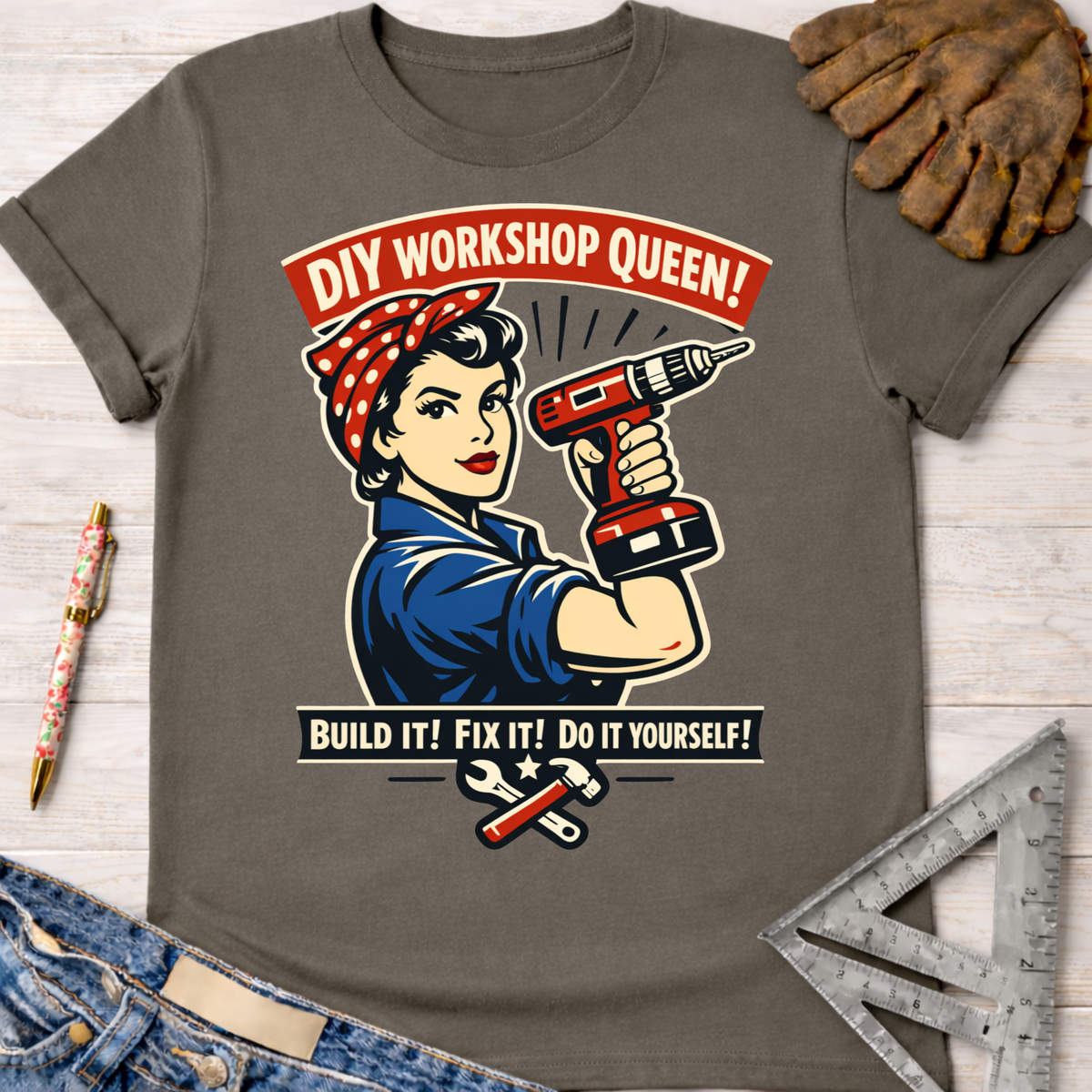 Women's funny woodworking graphic tee shirt for female woodworkers, makers, and DIY builders — Sawdust & Ponytails. Dark gray crew neck t-shirt with a Rosie the Riveter-style graphic holding a drill, "DIY Workshop Queen!" and "Build It! Fix It! Do It Yourself!" text.