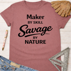 Women's funny woodworking graphic tee shirt for female woodworkers, makers, and DIY builders — Sawdust & Ponytails. Mauve cotton t-shirt with "Maker by Skill Savage by Nature" in black text.
