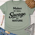 Women's funny woodworking graphic tee shirt for female woodworkers, makers, and DIY builders — Sawdust & Ponytails. Sage green cotton t-shirt with "Maker by Skill Savage by Nature" in black text.