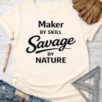 Women's funny woodworking graphic tee shirt for female woodworkers, makers, and DIY builders — Sawdust & Ponytails. Cream t-shirt with "Maker by Skill Savage by Nature" text.