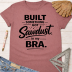 Women's funny woodworking graphic tee shirt for female woodworkers, makers, and DIY builders — Sawdust & Ponytails. Mauve cotton t-shirt with "Built Something Got Sawdust in my Bra" text.