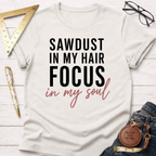 Cream cotton t-shirt with "Sawdust In My Hair Focus In My Soul" text, styled with jeans and tools.