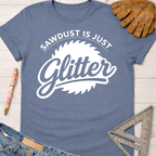 Women's funny woodworking graphic tee shirt for female woodworkers, makers, and DIY builders — Sawdust & Ponytails. A blue cotton t-shirt with "Sawdust Is Just Glitter" graphic.