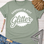 Women's funny woodworking graphic tee shirt for female woodworkers, makers, and DIY builders — Sawdust & Ponytails. Sage green cotton tee with "Sawdust Is Just Glitter" graphic.
