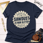 Navy blue "Sawdust Is Man Glitter" t-shirt with a saw blade graphic, styled on white wood.