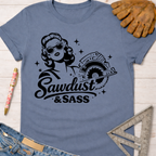 Women's funny woodworking graphic tee shirt for female woodworkers, makers, and DIY builders — Sawdust & Ponytails. Blue short-sleeve t-shirt with a black graphic of a sassy woman holding a circular saw and "Sawdust & Sass" text.