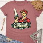 Mauve cotton t-shirt with a retro Rosie the Riveter-style woman holding a saw, text "Sawdust Spirit Glitter." Women's funny woodworking graphic tee shirt for female woodworkers, makers, and DIY builders — Sawdust & Ponytails