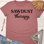 Women's funny woodworking graphic tee shirt for female woodworkers, makers, and DIY builders — Sawdust & Ponytails. Mauve cotton tee with "SAWDUST therapy." in black text.