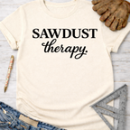 Women's funny woodworking graphic tee shirt for female woodworkers, makers, and DIY builders — Sawdust & Ponytails. Cream short-sleeve t-shirt with "SAWDUST therapy." in black script.
