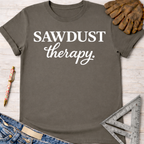 Women's funny woodworking graphic tee shirt for female woodworkers, makers, and DIY builders — Sawdust & Ponytails. Dark gray cotton tee with "SAWDUST therapy." in white text.