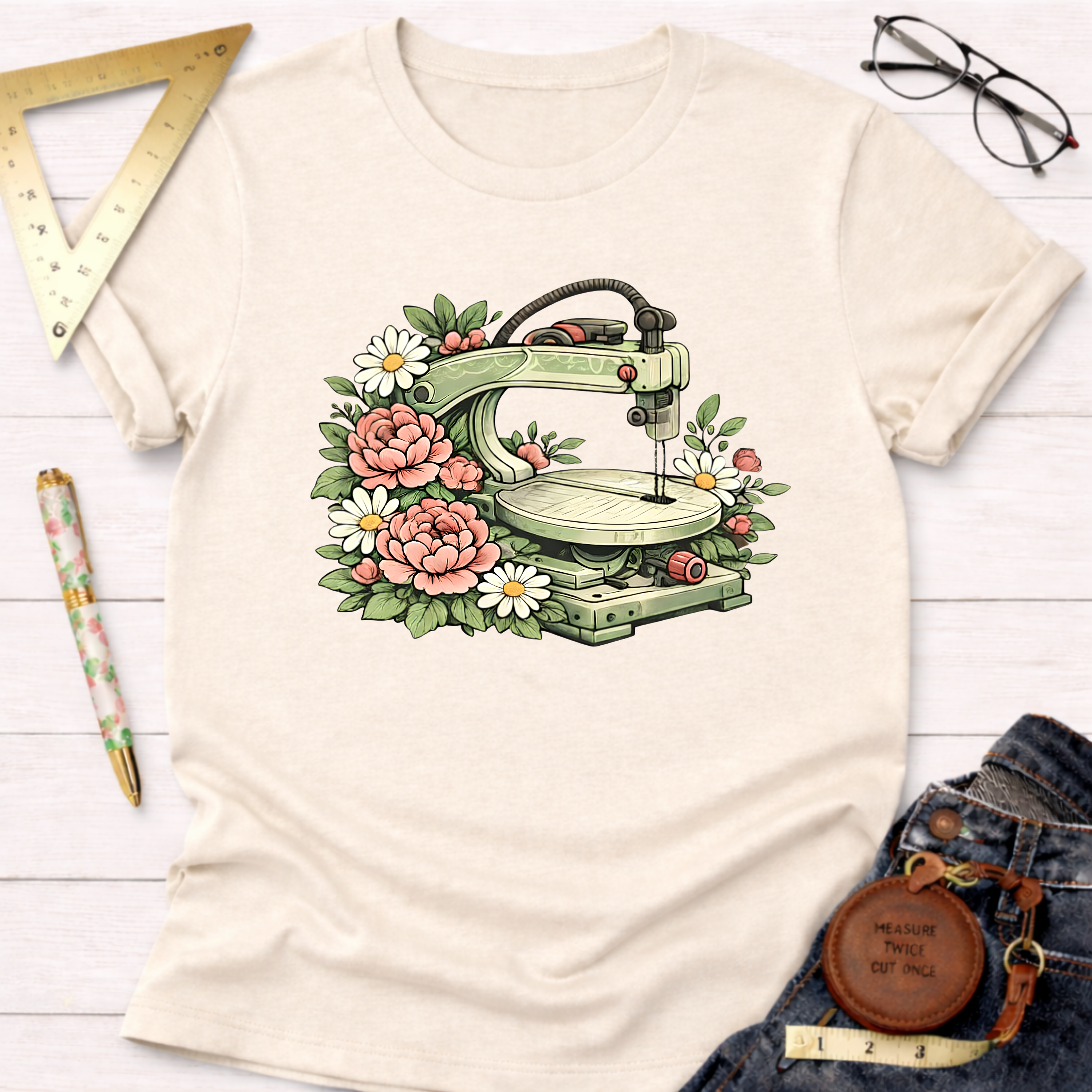 Beige "Scroll Queen" t-shirt with a green scroll saw surrounded by pink and white flowers.