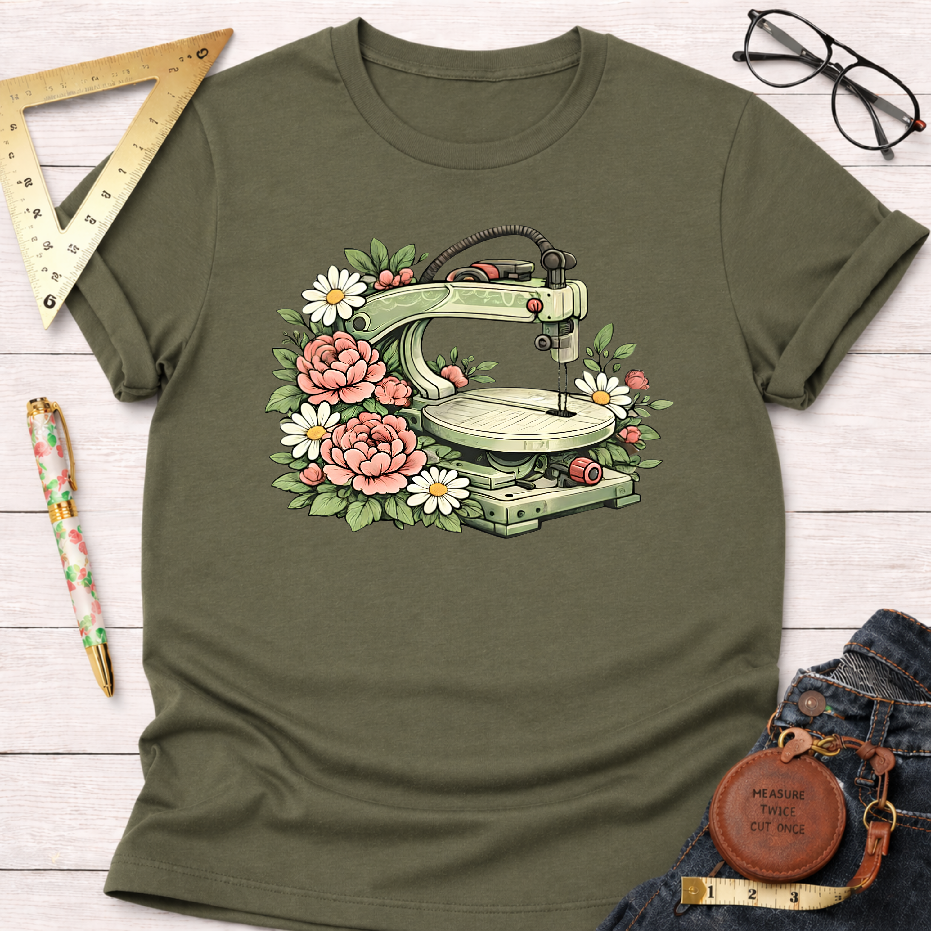 Olive green t-shirt with a scroll saw surrounded by pink peonies and white daisies.