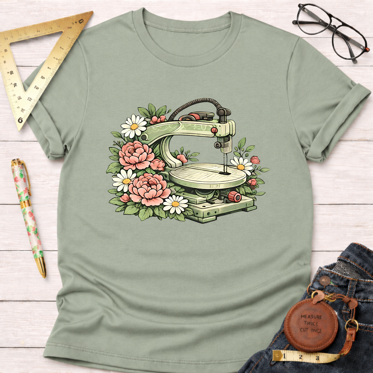 Sage green t-shirt with a scroll saw surrounded by pink roses and white daisies.