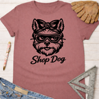 Women's funny woodworking graphic tee shirt for female woodworkers, makers, and DIY builders — Sawdust & Ponytails. Mauve t-shirt with a black "Shop Dog" graphic of a dog wearing glasses and a bow.